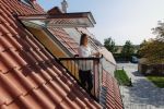 Frau und Mann stehen vor geöffnetem Dachfenster